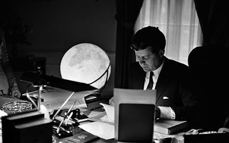 Photos of JFK at his desk, at the signing of a 1963 Farm Bill, and during a moment of smilingly engaging an audience.